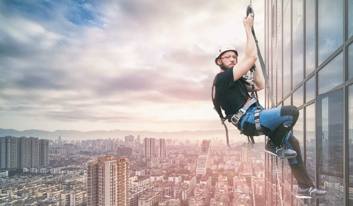 Un uomo è appeso sul lato di un edificio.